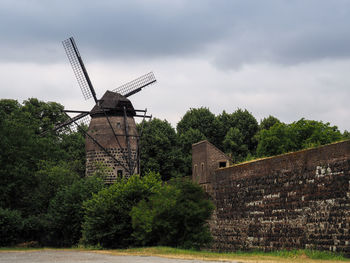 Traditional windmill on landscape against sky