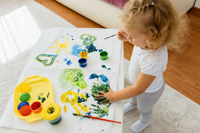 Toddler girl painting at home. happy creative child spending time with fun and joy. learning colours