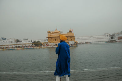 Rear view of senior man against sky in city