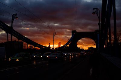 Cars on bridge against dramatic sky