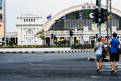 Rear view of people walking on road along buildings