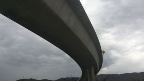 Low angle view of bridge against cloudy sky