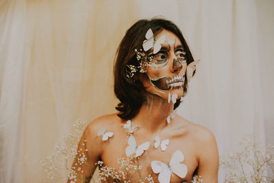 Portrait of young woman standing against wall