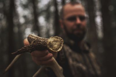 Portrait of man holding antler in forest