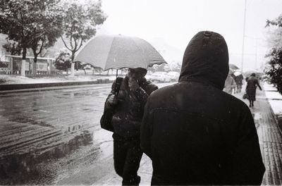 Rear view of people on wet street during rainy season