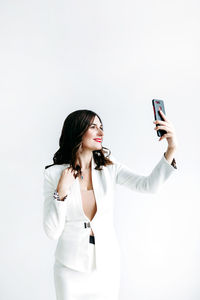 Woman photographing with mobile phone against white background