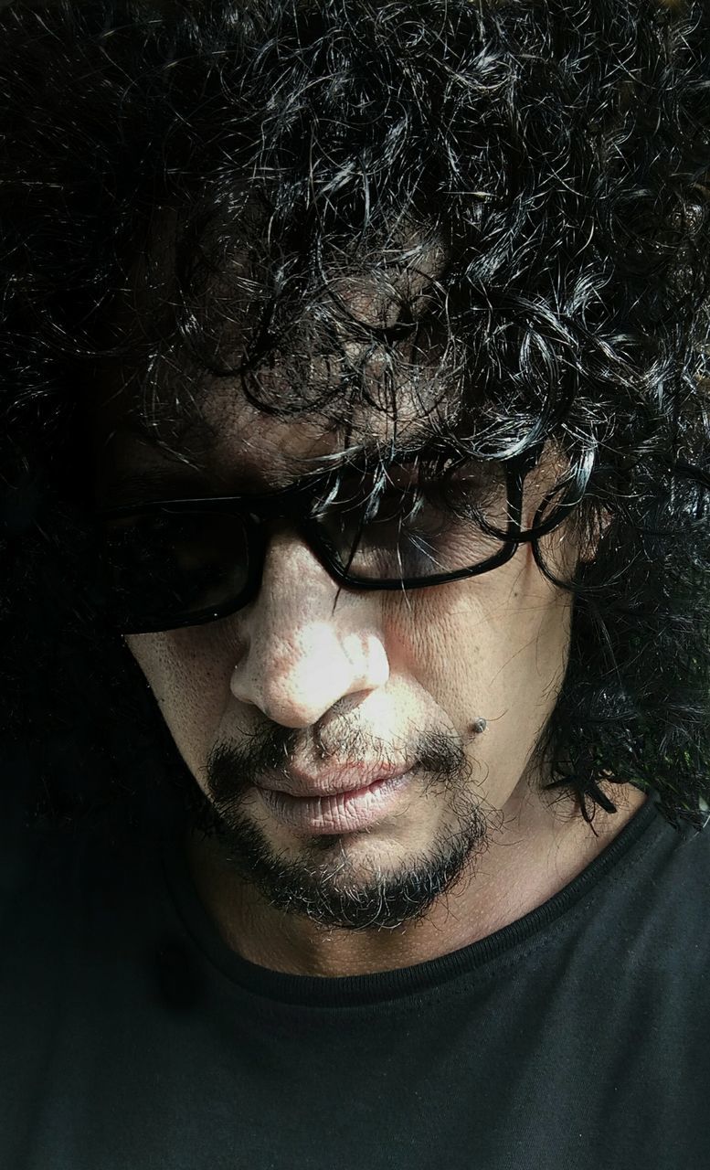 portrait, one person, black, headshot, human hair, adult, human face, beard, hairstyle, glasses, young adult, front view, men, close-up, facial hair, darkness, serious, indoors, looking at camera, person, human head, fashion, studio shot, eyeglasses, nose, lifestyles, stubble, vision care, moustache, dark