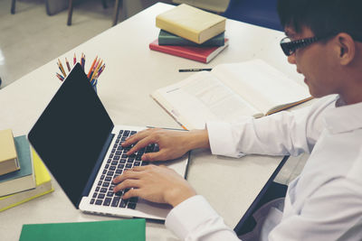 Male student using laptop while sitting at table in library