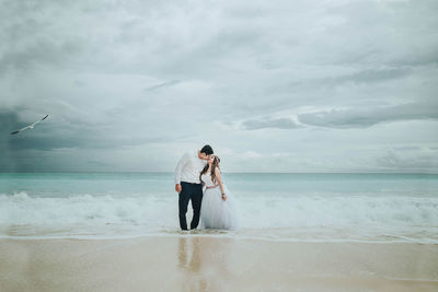 Rear view of couple standing on beach