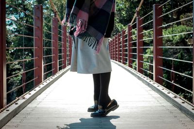 Low section of woman tiptoeing on footbridge