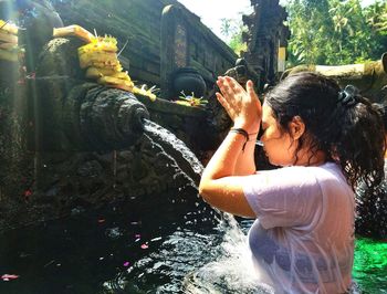 Side view of woman praying in pond