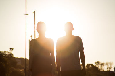 Low angle view of man and woman standing against sun