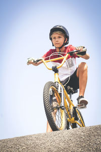 Low angle view of boy riding bicycle on sports ramp against clear sky