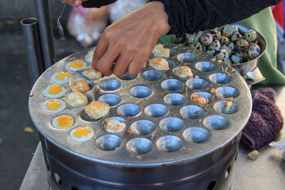 Cropped hands preparing eggs on baking sheet at street market