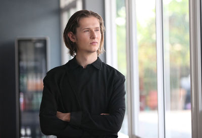 Portrait of young man looking through window