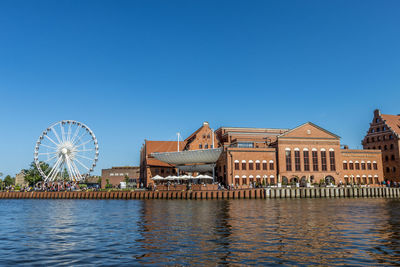 View of ferris wheel and buildings against clear blue sky