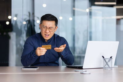 Portrait of young man using mobile phone at office