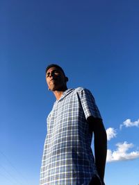 Low angle view of man looking away against blue sky