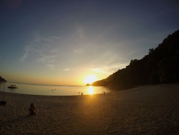 Silhouette man standing on beach against sky during sunset