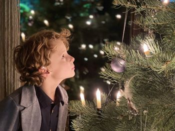 Rear view of boy looking at illuminated christmas tree