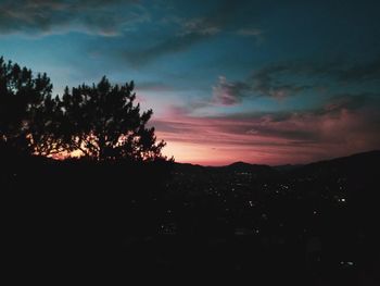 Silhouette trees on landscape against sky during sunset