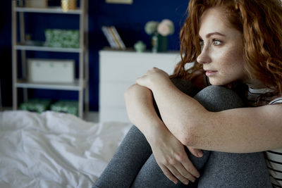 Portrait of young woman sitting on bed at home