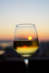 Close-up of beer glass against sky during sunset