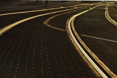Low angle view of empty road and rails in evening light 