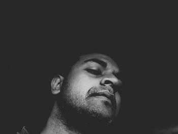 Close-up portrait of young man against black background