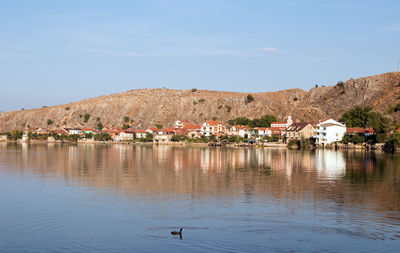 Scenic view of lake and houses against sky