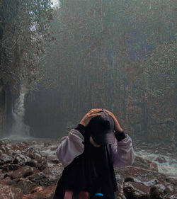 Rear view of woman standing against trees in forest