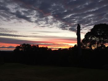 Silhouette of trees on field against sky at sunset