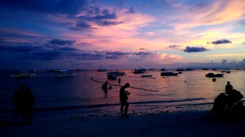 Silhouette people on beach against sky during sunset