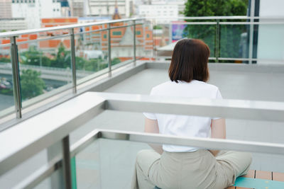 Solo asian woman during outdoor break and relax at rooftop with city background