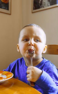 Portrait of boy eating food at home