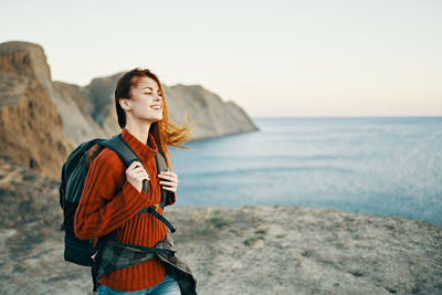 Young woman standing by sea against sky