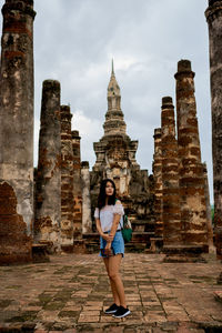 Full length of young woman standing outside temple against building