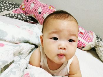 Close-up of cute baby girl lying on bed at home