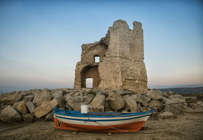 Boat moored on beach against clear sky