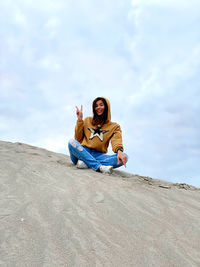 Young woman sitting on sofa against sky