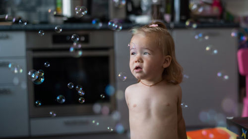 Portrait of shirtless boy looking at bubbles