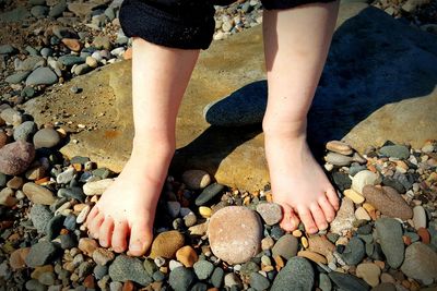 Low section of child standing on pebbles at beach