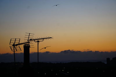 Low angle view of birds flying against sky during sunset