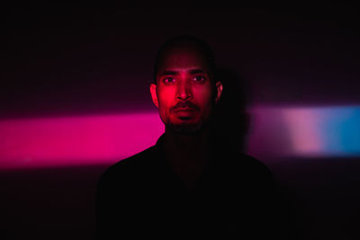 Portrait of young man standing against illuminated wall