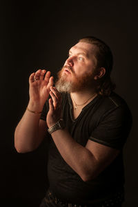 Young man looking away against black background