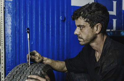 Side view mechanic using caliper while checking, measuring car tire tread in professional workshop