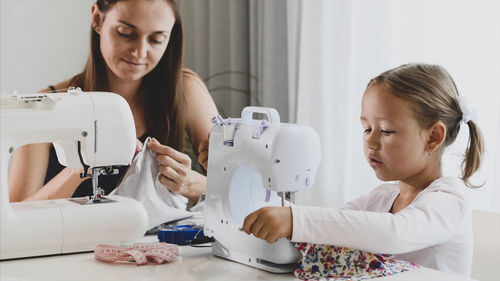 Mother and daughter sewing clothing at home