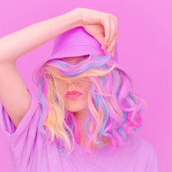 Close-up of woman with pink hat against colored background