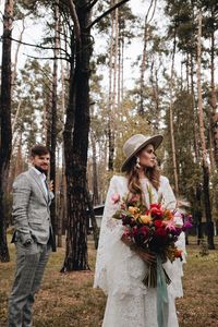 Couple with bouquet standing in forest