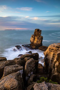 Rocks on shore by sea against sky